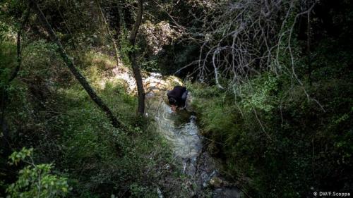 Беженец пьет воду из ручья по дороге во Францию